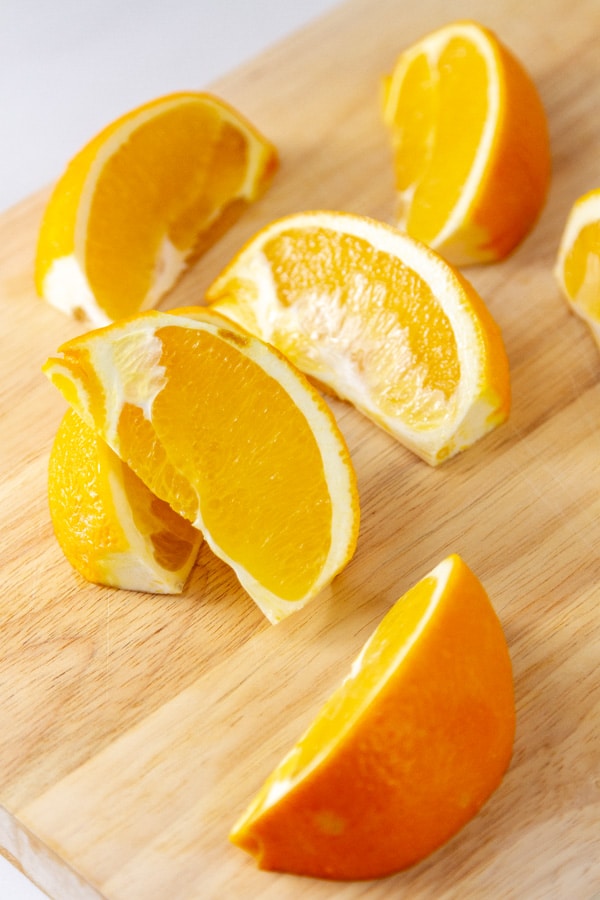 sliced oranges on a wooden cutting board.