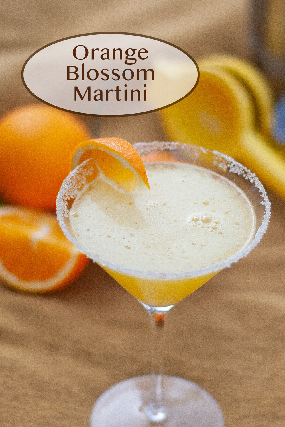 Orange Blossom Martini in a martini glass in front of oranges and a citrus squeezer.