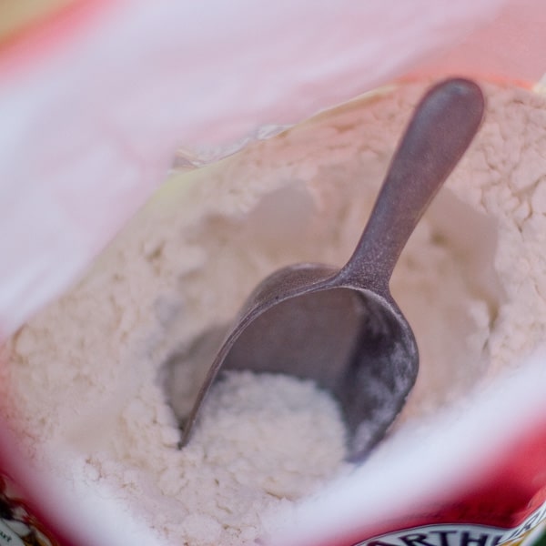 a metal scoop in a bag of flour.