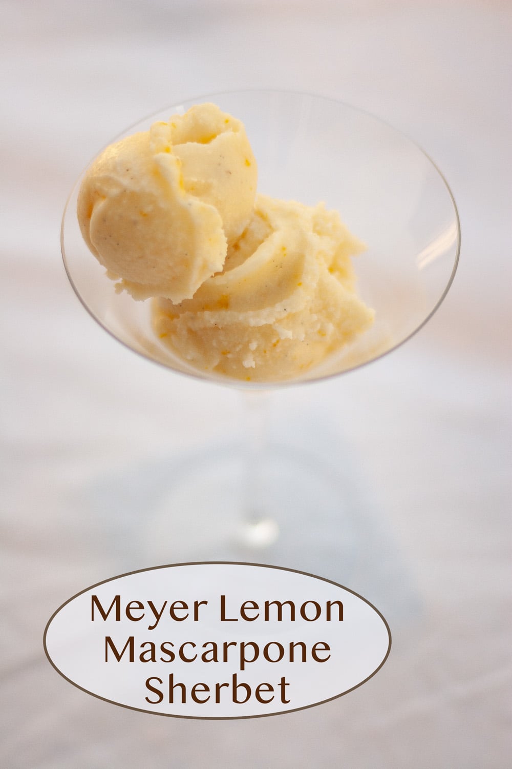 a martini glass filled with two scoops of ice cream on a white background.