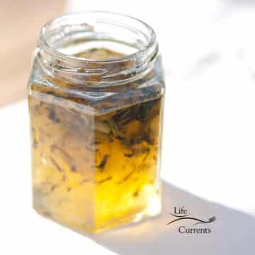 square crop of a glass jar filled with zucchini jam on a white table cloth.