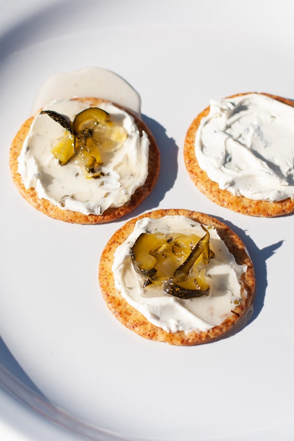 three crackers with cream cheese and jam on them.