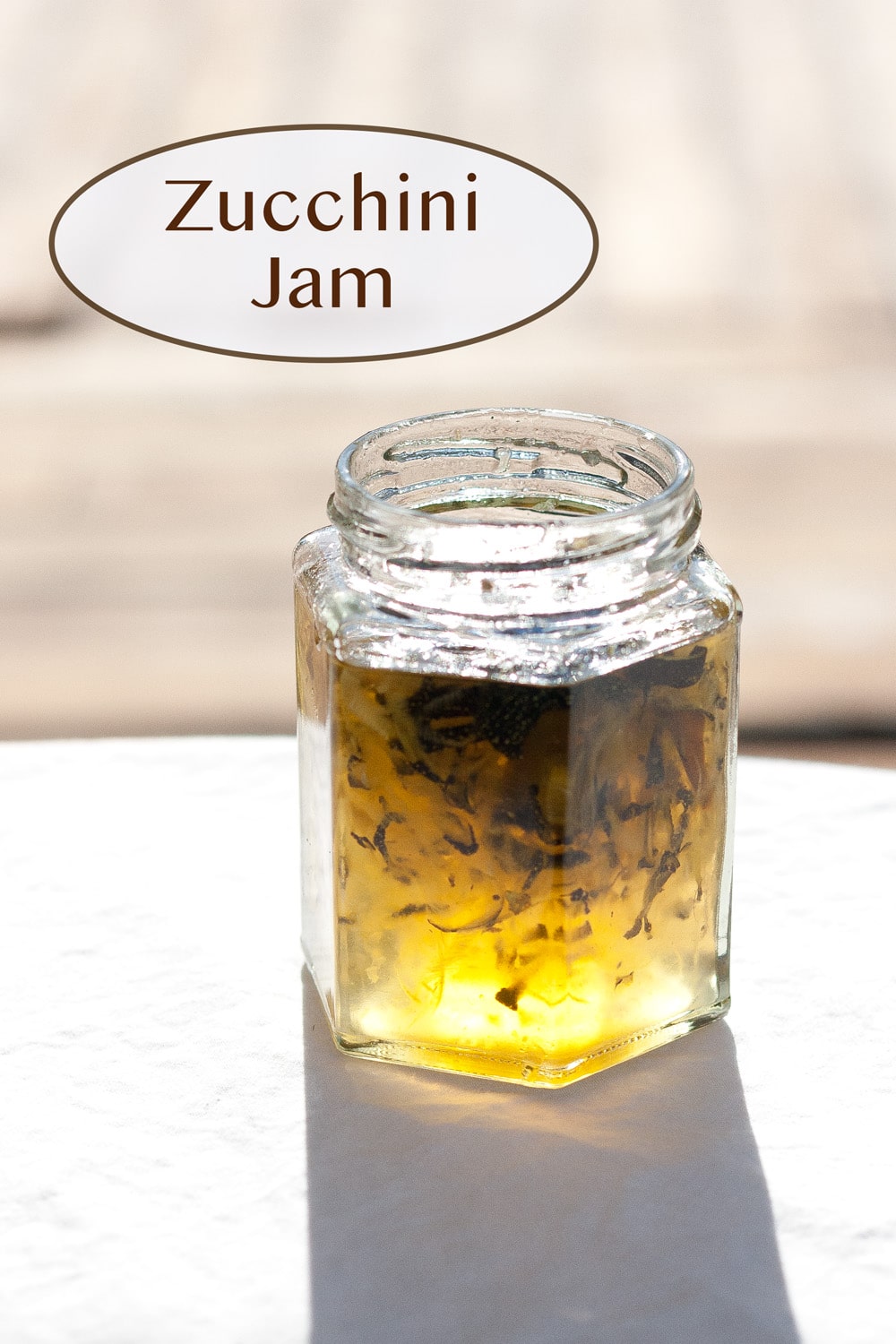 a small jar fille with jam and the sunlight is coming through so you can see the yellow color shine.