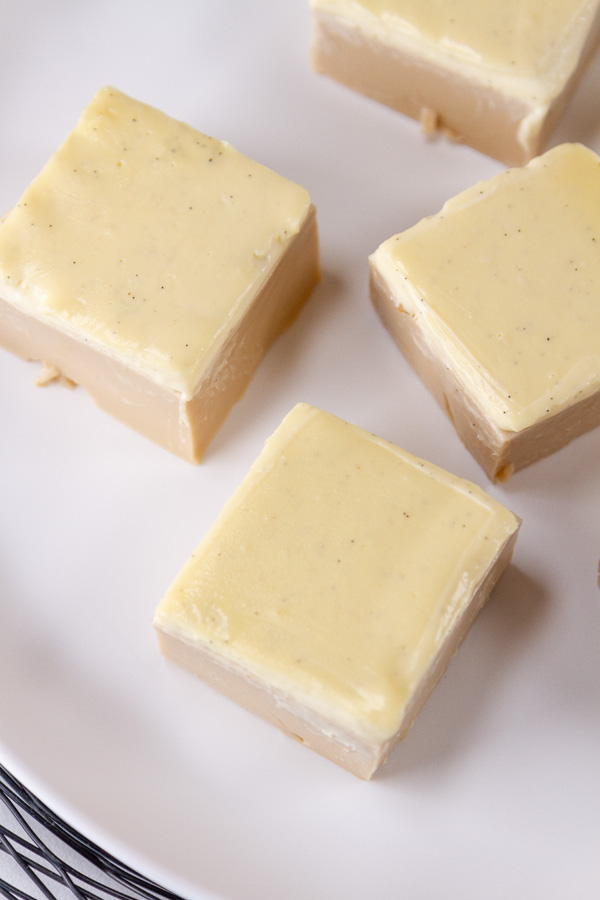 looking down on some squares of coffee jelly with cream topping on a white plate.