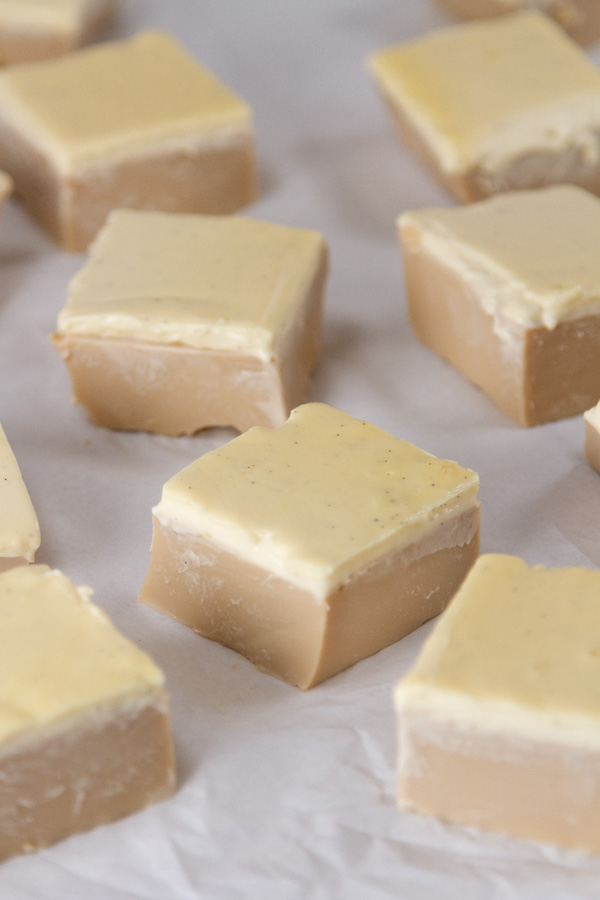 several coffee jelly squares with cold foam topping on white parchment paper.