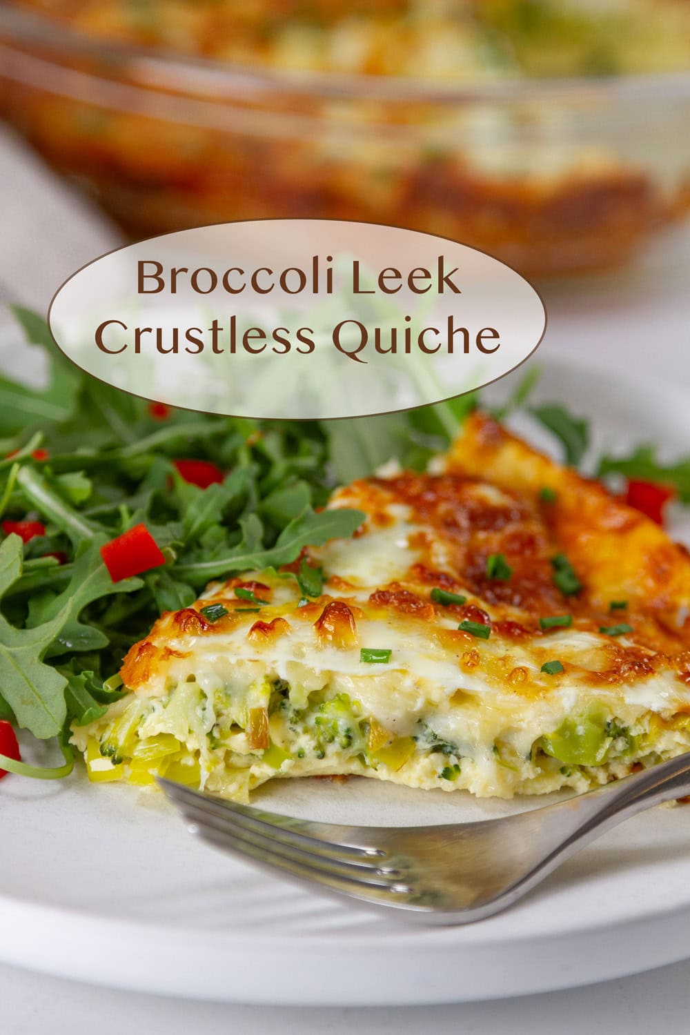 a slice of crustless quiche on a plate with arugula salad and a fork.