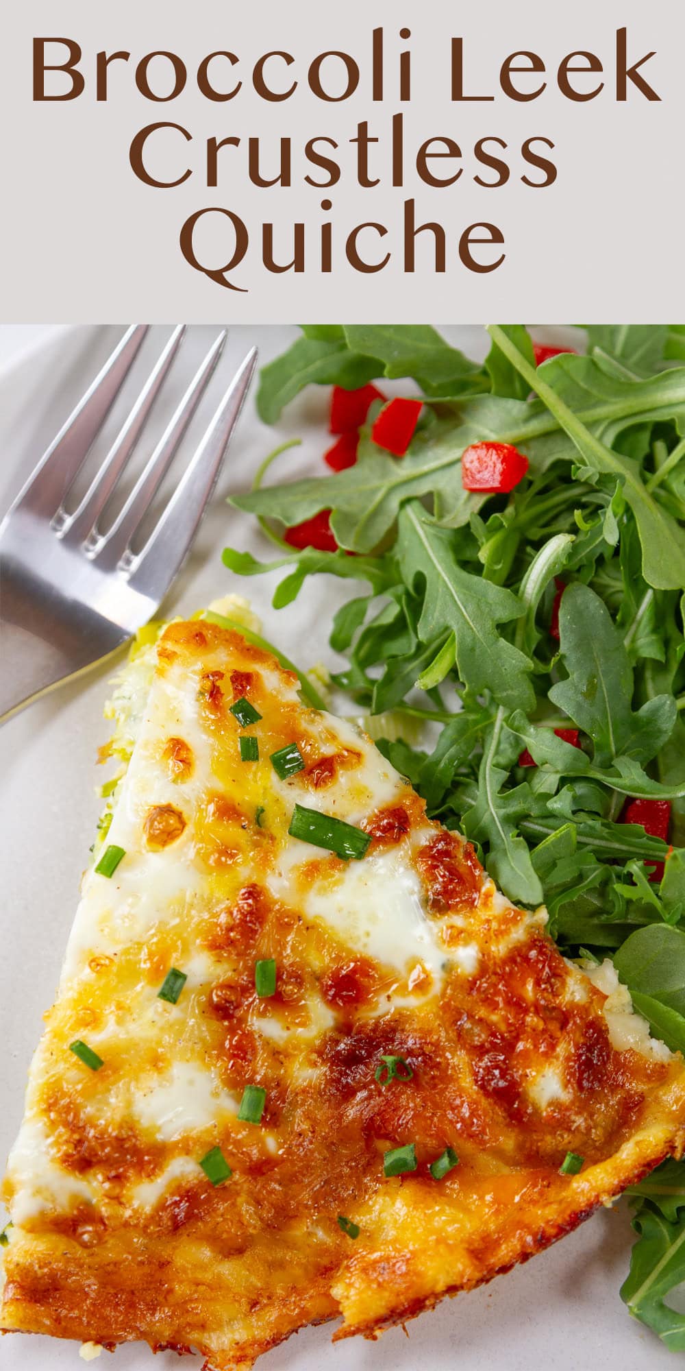 looking down on a slice of cheesy quiche with a salad next to it.