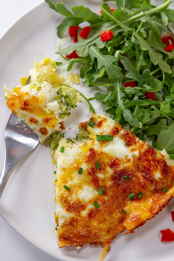 looking down on a plate of quiche and salad with a bite taken out of the quiche.