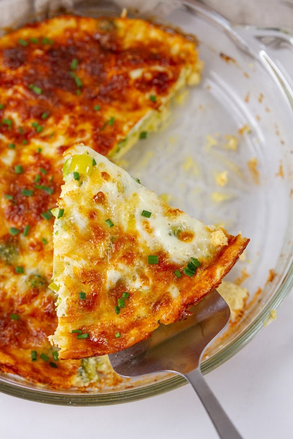 taking a slice of quiche from the pan.
