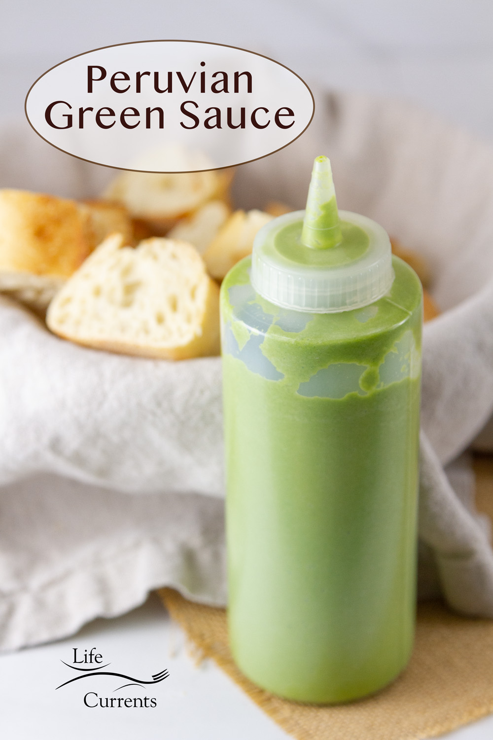 a squeeze bottle filled with Peruvian Green Aji Sauce in front of a basket of bread slices.