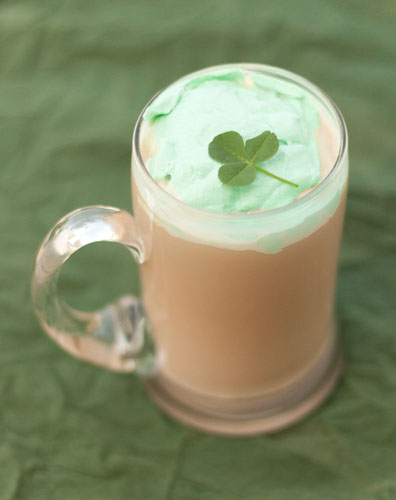 Kiss of the Irish Coffee with green whipped cream in a glass mug.