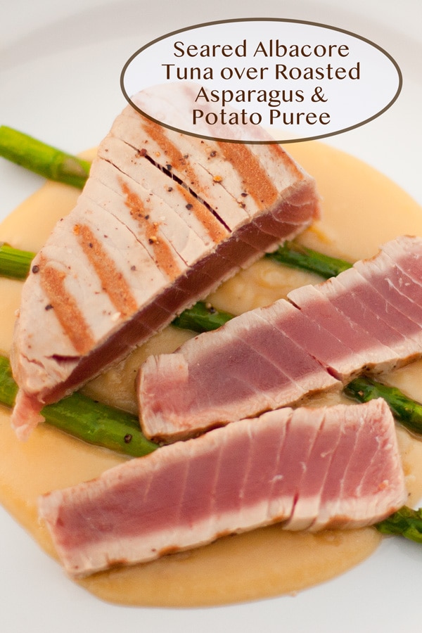 Seared Albacore Tuna over Roasted Asparagus and Potato Puree on a white plate.