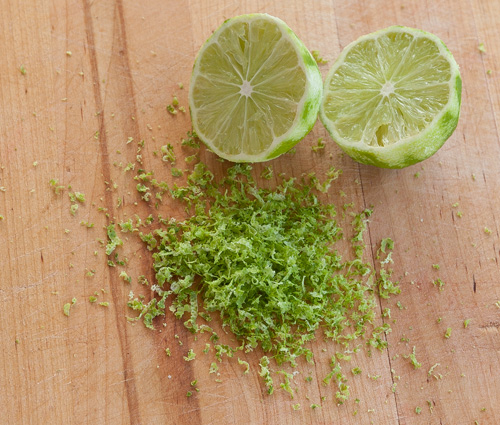 a lime cut in half next to a pile of lime zest.