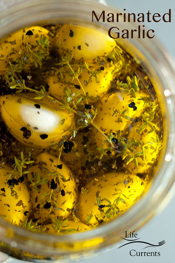 MARINATED GARLIC in a glass jar with lots og herbs and spices and a title