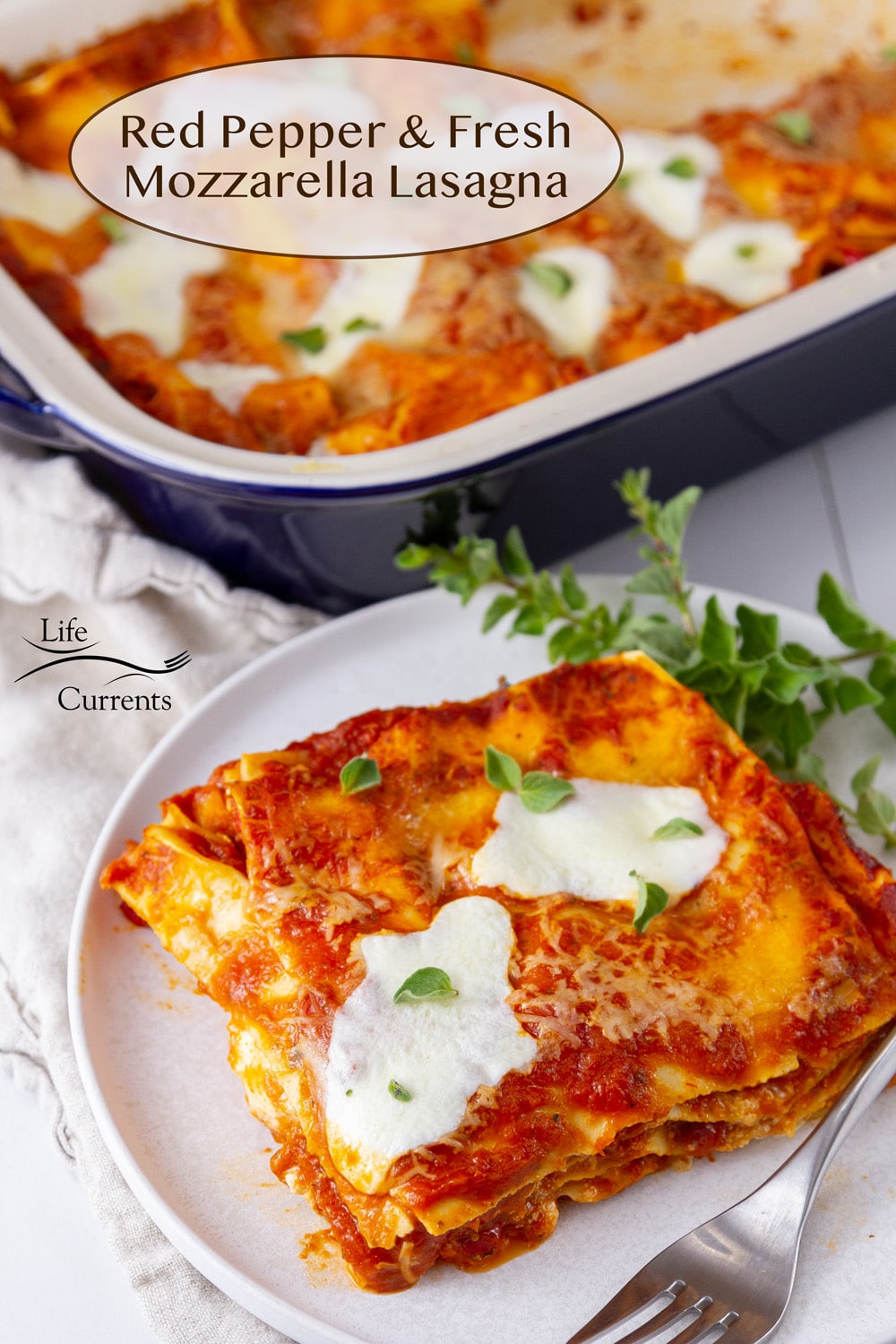 a large serving of Red Pepper Fresh Mozzarella Lasagna on a white plate with a fork in front of the whole casserole dish of lasagna.
