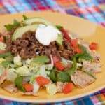 square crop of a taco salad topped with lentils avocado and sour cream.