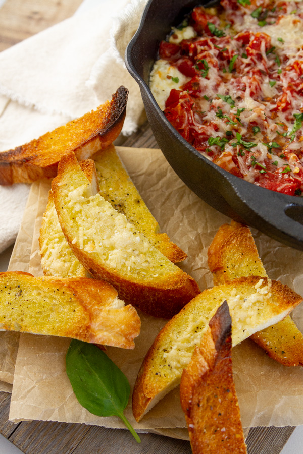 bread sticks next to a pan of dip.