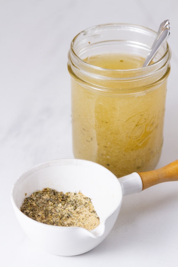 a glass mason jar filled with broth and the dry broth mix in a measuring cup in front.