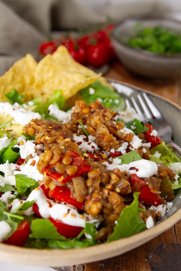 lentil taco bowl with sour cream and chips and a fork on the right.
