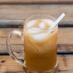 a glass mug with almond coffee, iced, and a straw in it.