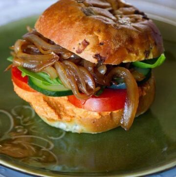 Roasted red pepper hummus sandwich with tomatoes, cucumbers, and caramalized onions. A Veggie vegetarian, vegan delight!
