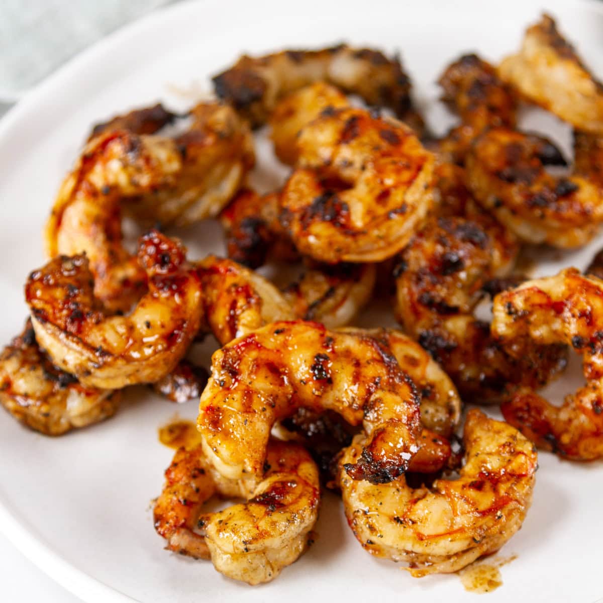 square crop of grilled shrimp on a white plate.