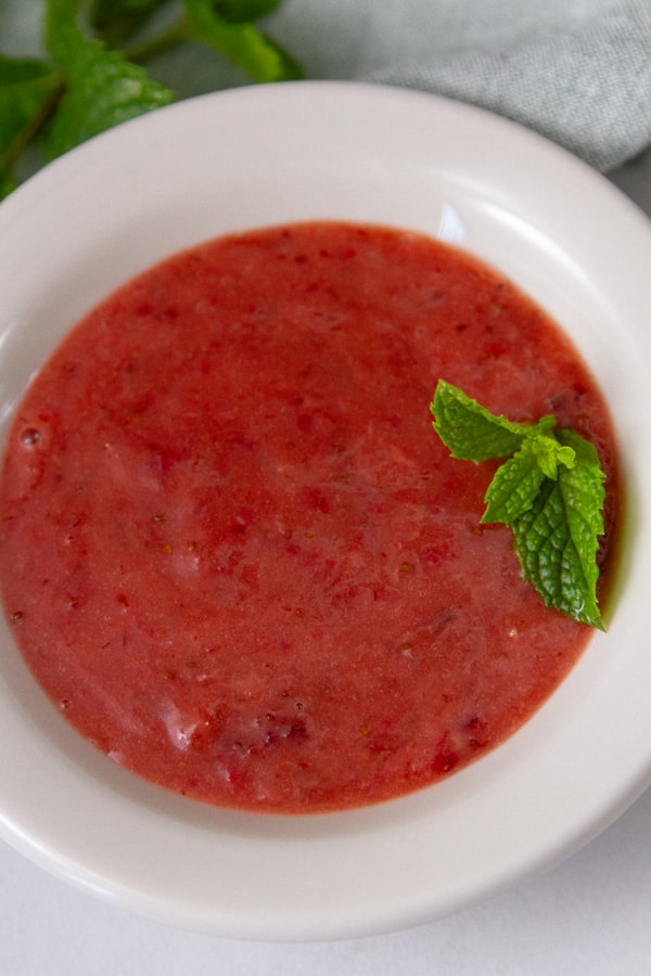roasted strawberry sauce in a white bowl with fresh mint garnish.