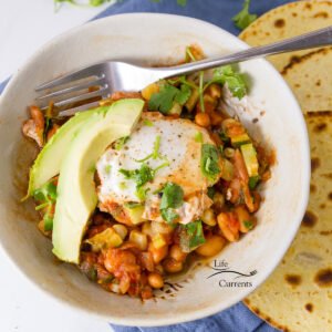 square crop of egg, veggies, beans in a bowl with avocado