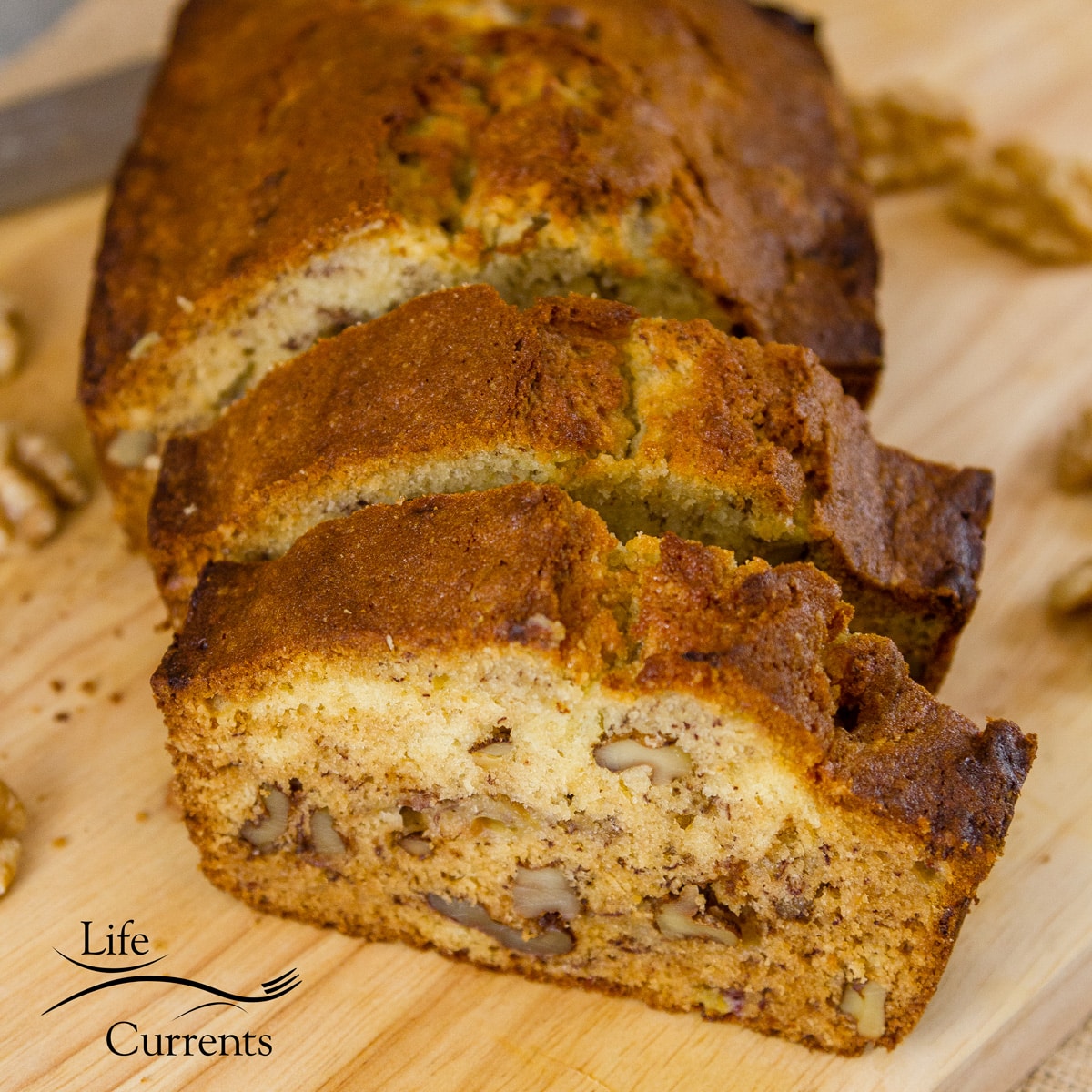 a loaf of banana bread that's been sliced into two slices and some walnuts around the bread.