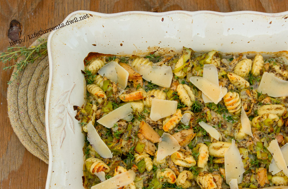 Looking down on a baking dish full of casserole garnished with pieces of Parmesan cheese.