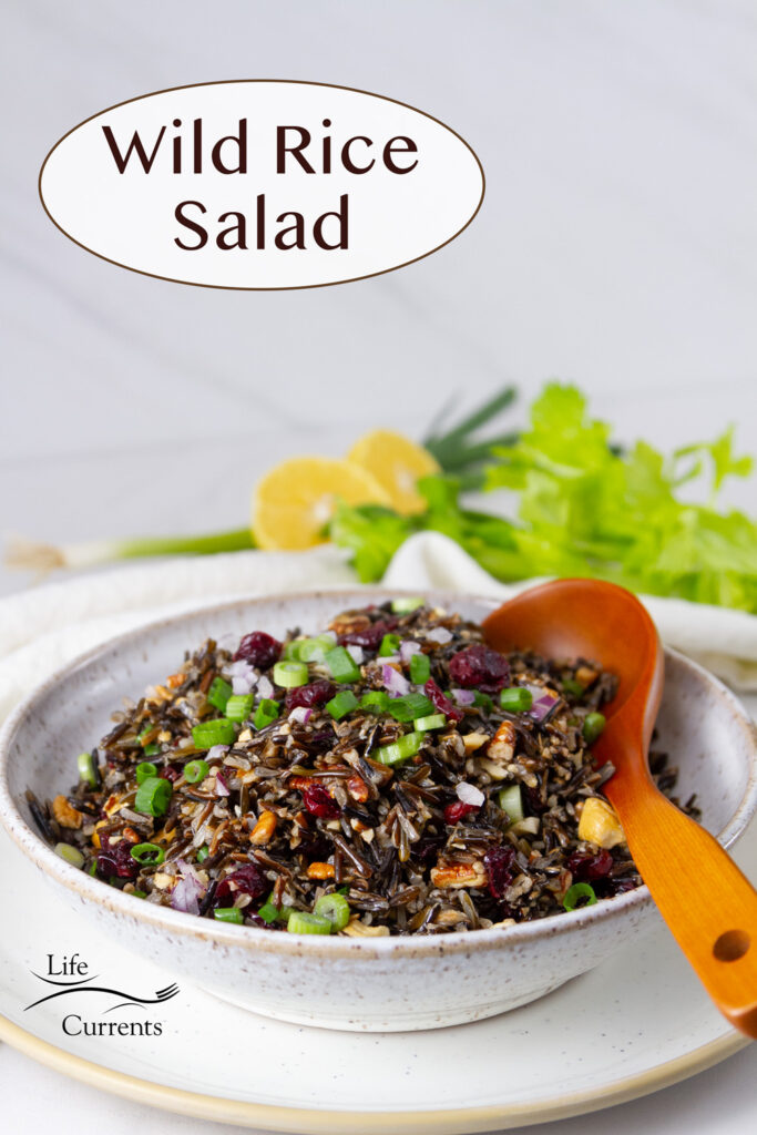 wild rice salad in a white bowl with a wooden spoon, title on upper left.