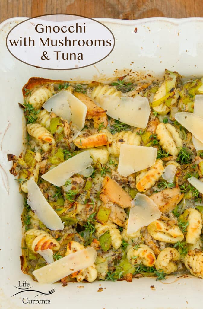 a casserole dish with a baked casserole of gnocchi, mushrooms, cheese, and tuna garnished with thyme, title on top: Gnocchi with mushrroms and tuna.