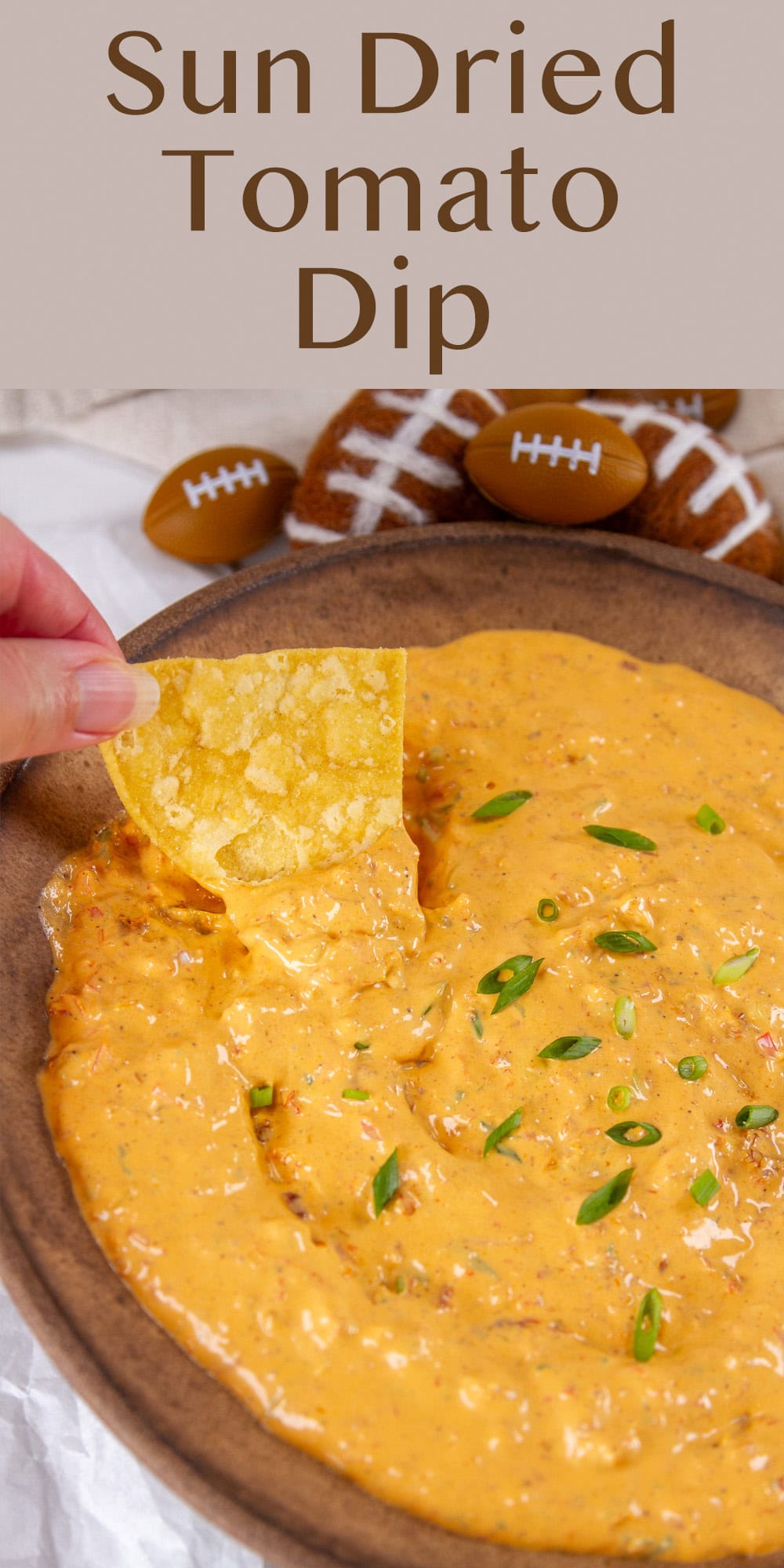 a tortilla chip being dipped into dip and some football decorations around it.