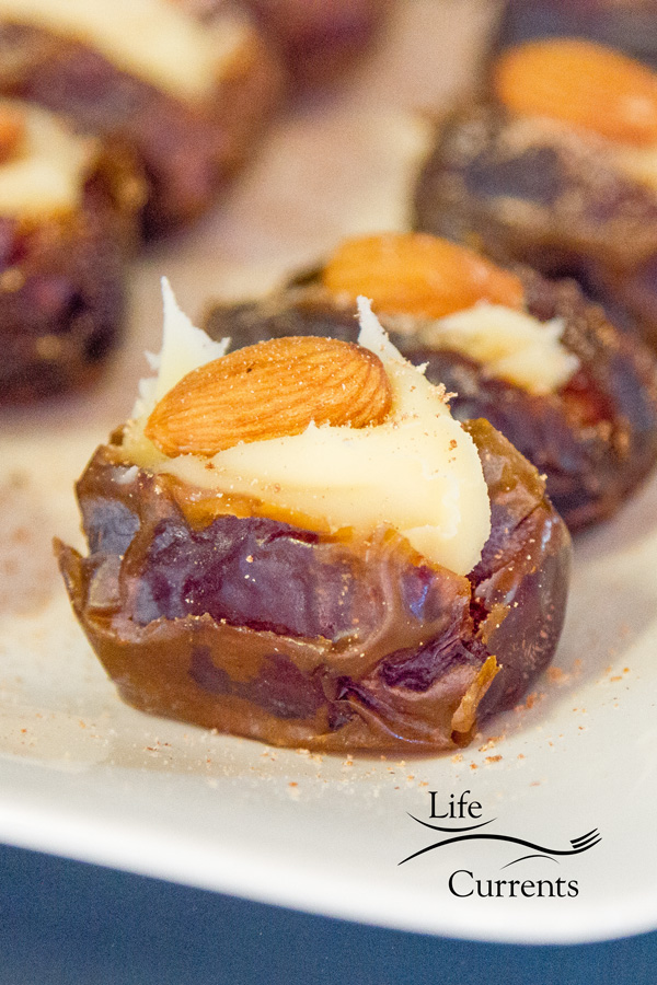 Medjool dates stuffed with Mascarpone, an almond, and garnished with freshly ground nutmeg on a white plate