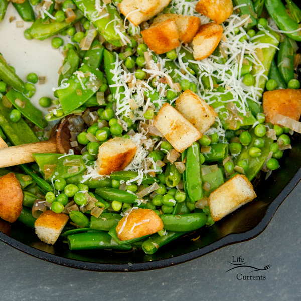 peas, croutons, and parmesan cheese in a cast iron skillet 