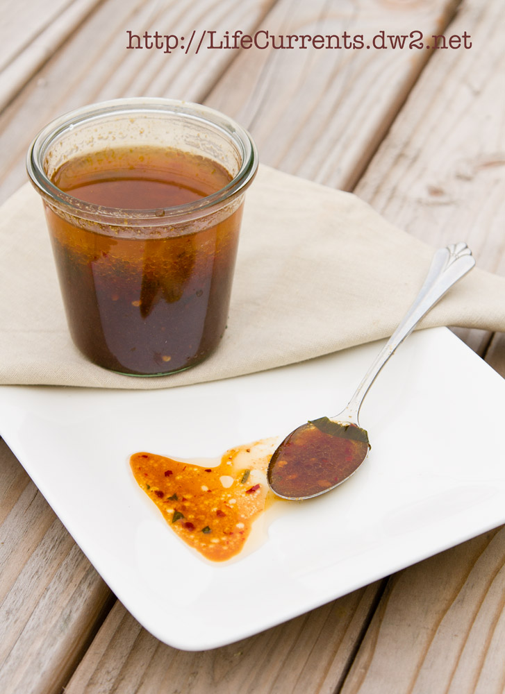 marinade in a glass jar with a spoon full and a drizzle in front of it, all on a white plate.
