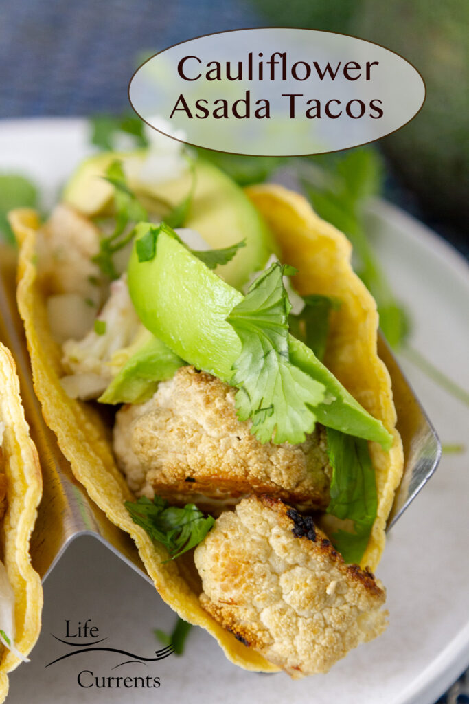 Cauliflower asada tacos garnished with avocado and cilantro.