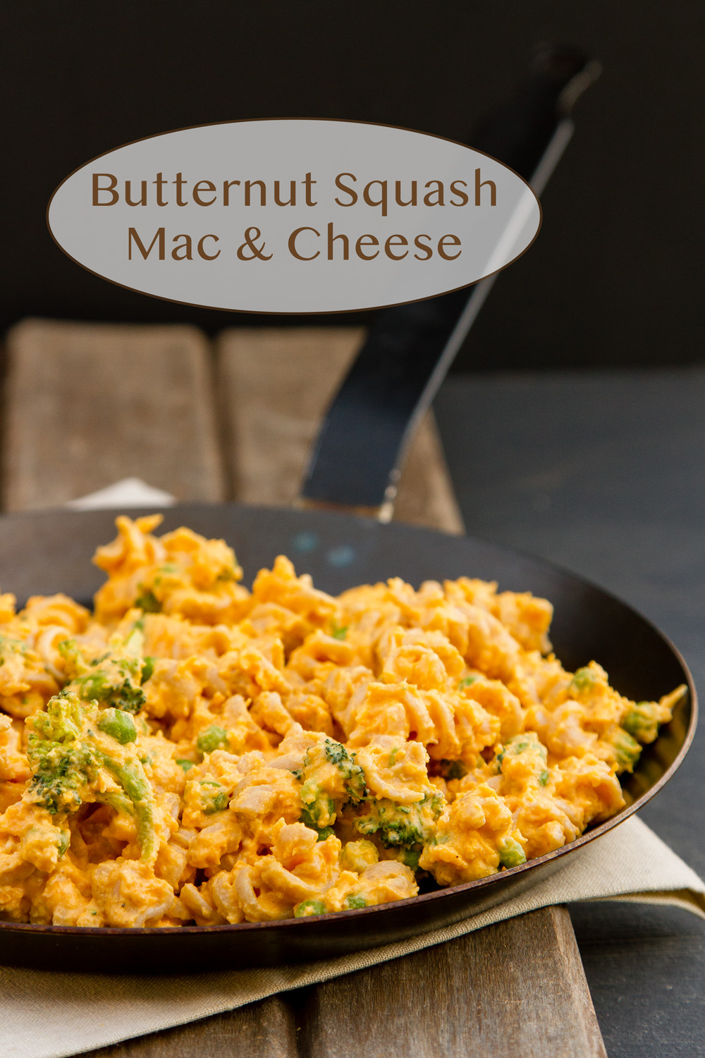 pasta with vegetables and cheese in a skillet on a wooden background.