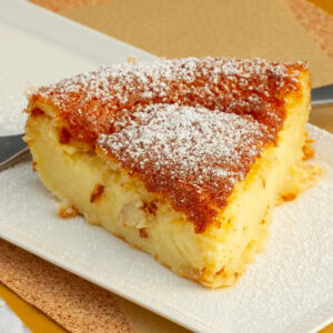 square crop looking at a slice of tart on a white plate with a fork behind it.