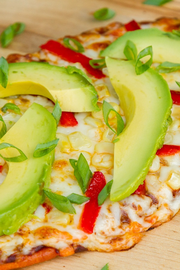 close up on a cheesy flatbread where the cheese is dripping off the side.