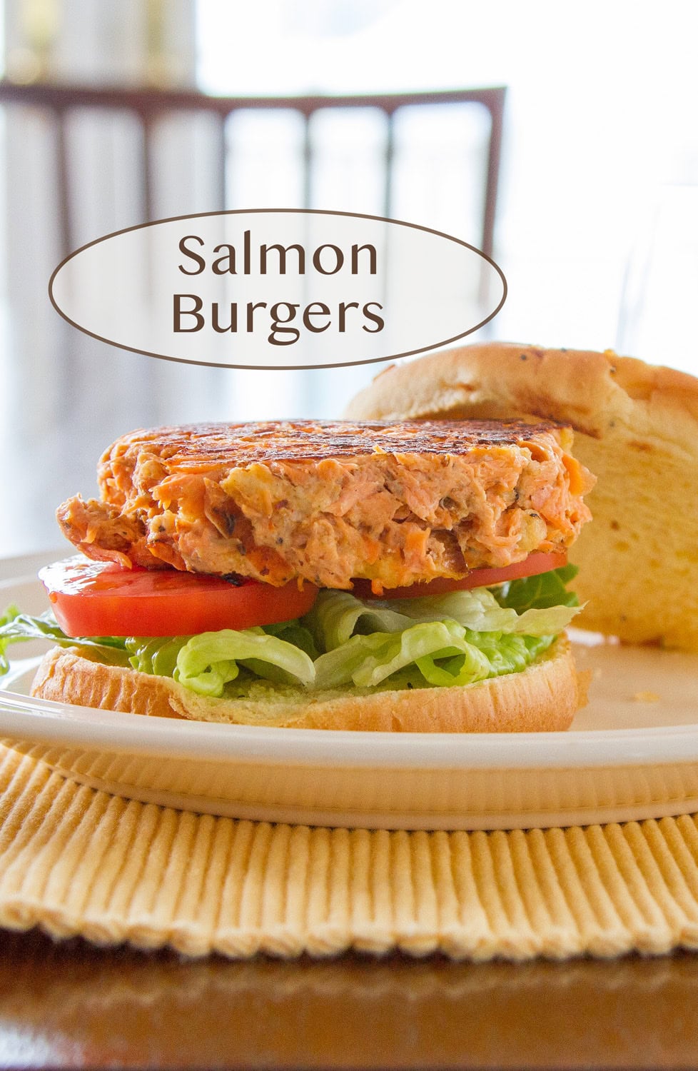 a salmon burger on a bun with lettuce and tomato.