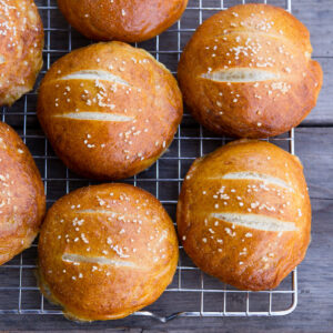 square crop looking down on pretzel buns on a wire rack cooling.