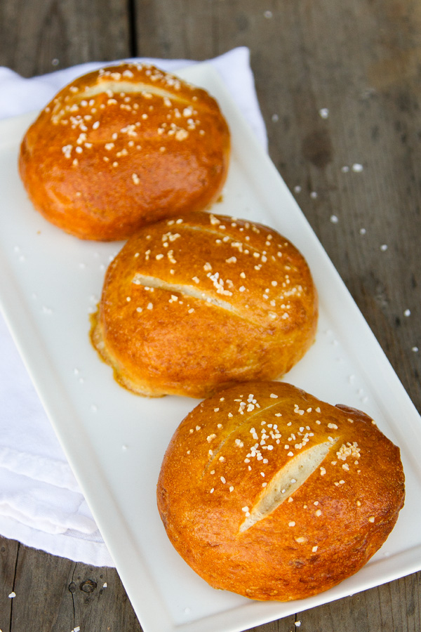 three pretzel rolls on a white plate.