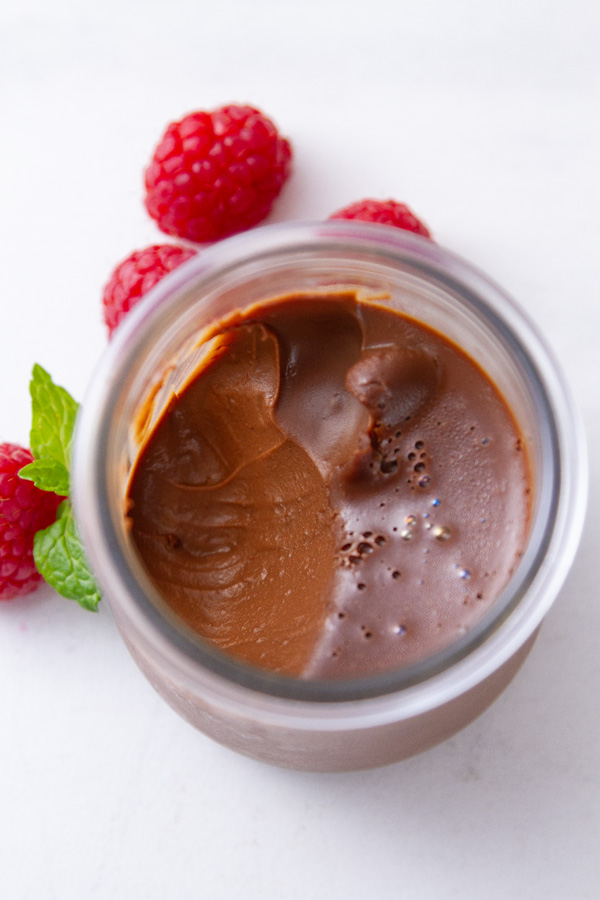 looking down into a glass jar with mousse, and a bite has been taken out.