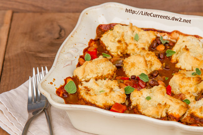 casserole in a casserole dish with biscuit toppings and two forks next to it.