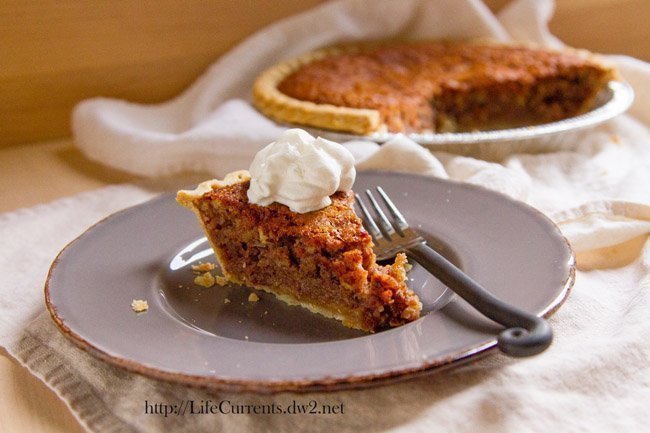 a slice of pie on a grey plate with a fork, the rest of the pie is in the background.