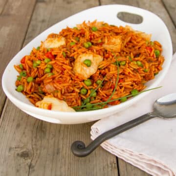 a white bowl filled with cooked orzo and veggies with a cloth napkin and spoon next to it.