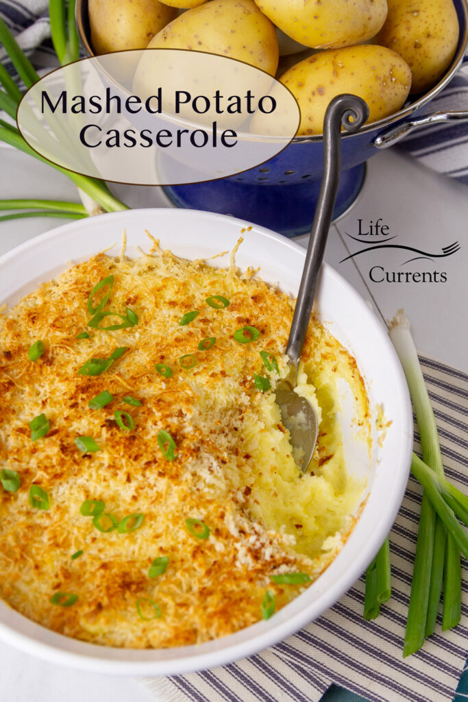 Mashed Potato Casserole with a serving taken out of it and some potatoes behind it.