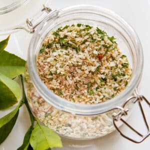 Homemade Onion Soup Mix in a glass jar with green leaves next to it.