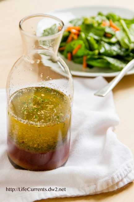 I bottle of Italian dressing in front of a salad.